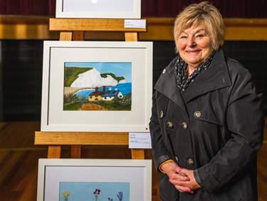 Susie Brooke - Artist from Encircle standing next to her art work displayed on an easel