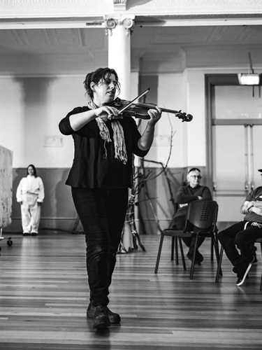 Rachel Meyers – a black and  white photo of a female playing the violin in front of a crowd at the ATC 2021 launch event at City Hall