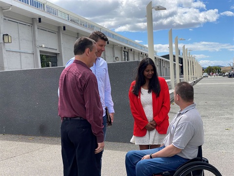 Four individuals standing outside PW1 discussing accessibility changes for the 2021 Taste of Summer