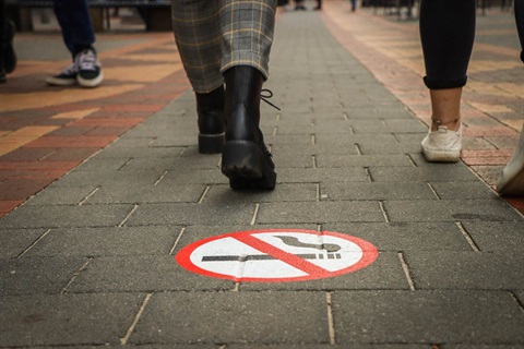 feet walking over smoke free sign