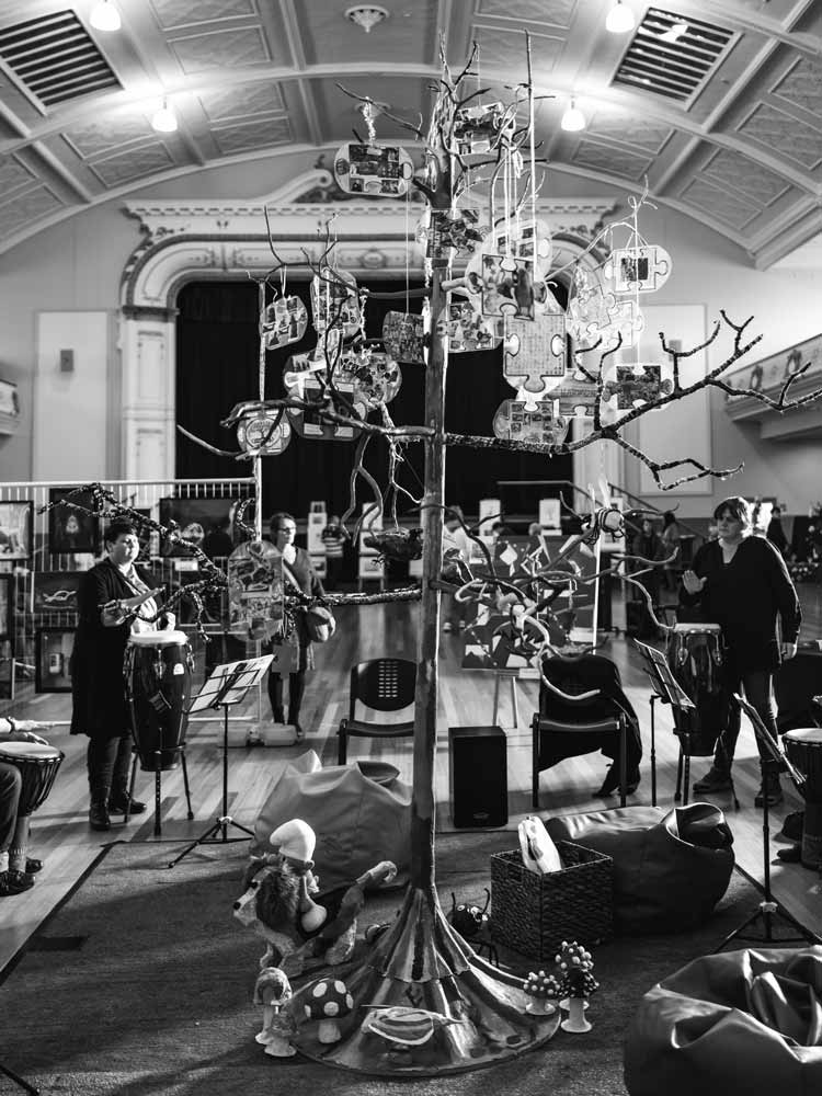 A black and white image of a tree and people standing around the tree drumming by Langford Support Services A black and white image of a tree and people standing around the tree drumming by Langford Support Services