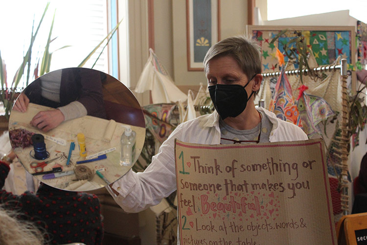 A person holding a mirror and a sign reading 'Think of something or someone that makes you feel beautiful'.