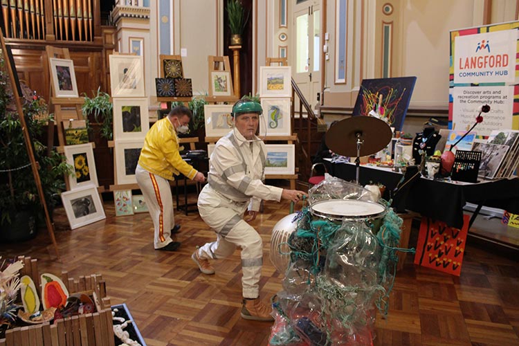 Two dancers moving around the exhibition with a large drum.