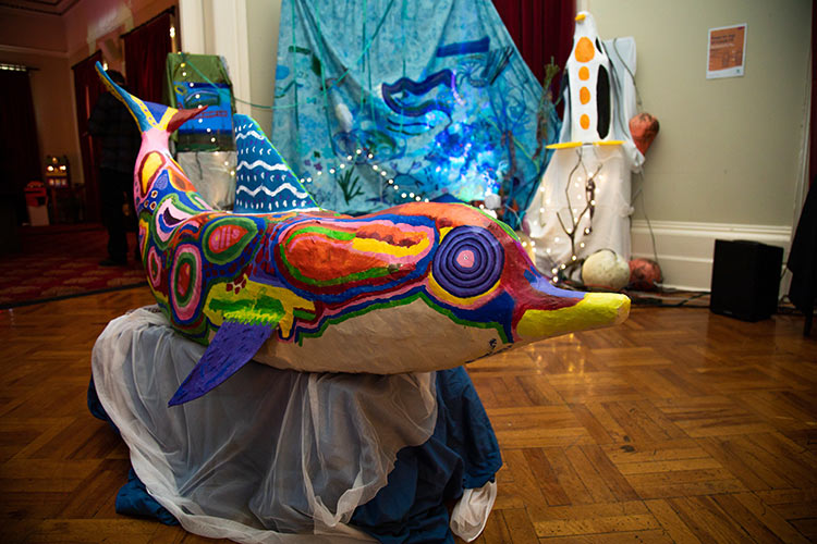 A large scale dolphin painted with bright colourful patterns and shapes.