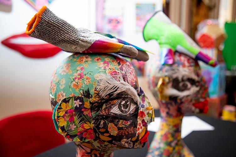 Two large colourful paper mache heads with a glove sitting on the top.
