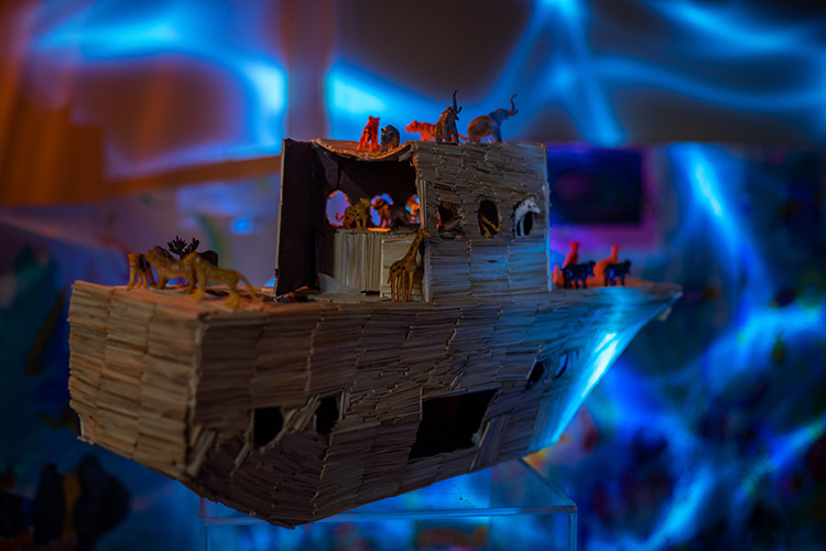 A boat made of small wooden sticks with a back drop of waves of the sea.