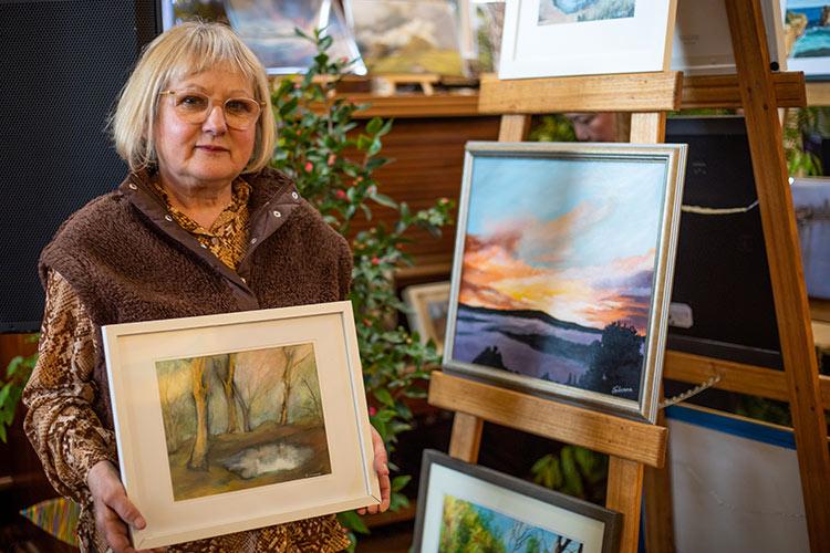 Afternoon Delight artist standing next to her art work displayed on an easel.