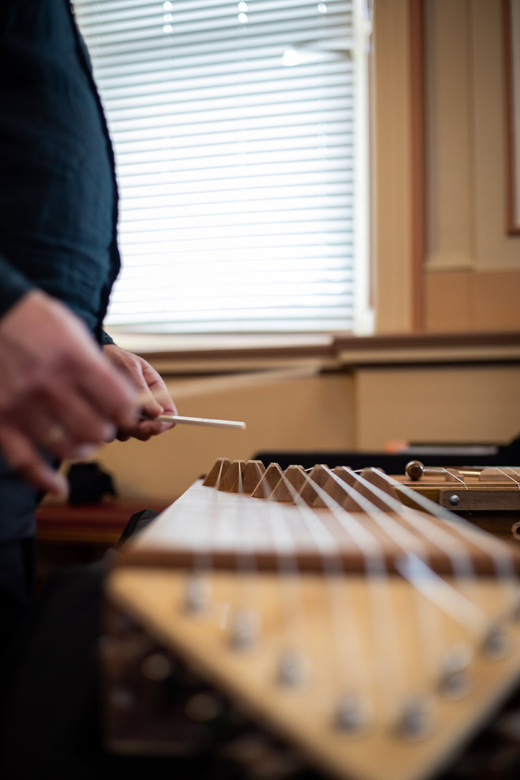 Up close image of a wooden string instrument being played.