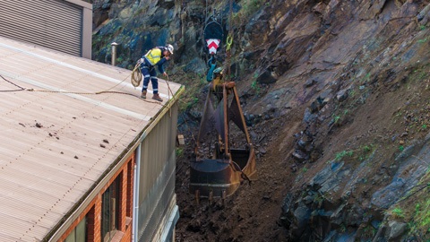 Man on top of building managing rockfall remediation