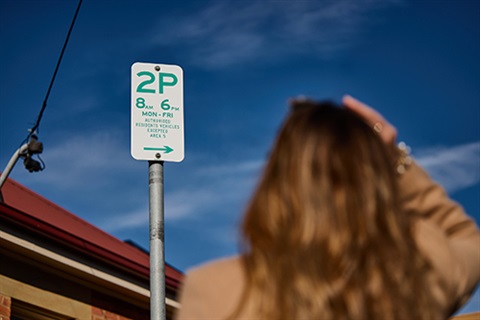 Person reading a parking sign